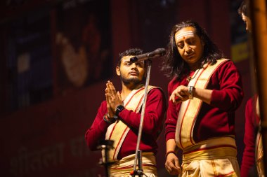 Varanasi, Uttar Pradesh, Hindistan - 20 Ocak 2024: Ganga aarti, Dashashwamedh ghat geleneksel elbise ve Hindu ayinleri ile kutsal nehir keneviri akşam ayini yapan genç bir rahibin portresi.