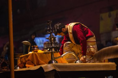 Varanasi, Uttar Pradesh, Hindistan - 20 Ocak 2024: Ganga aarti, Dashashwamedh ghat geleneksel elbise ve Hindu ayinleri ile kutsal nehir keneviri akşam ayini yapan genç bir rahibin portresi.