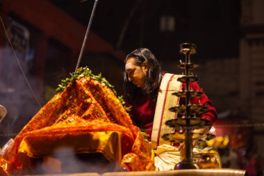 Varanasi, Uttar Pradesh, Hindistan - 20 Ocak 2024: Ganga aarti, Dashashwamedh ghat geleneksel elbise ve Hindu ayinleri ile kutsal nehir keneviri akşam ayini yapan genç bir rahibin portresi.