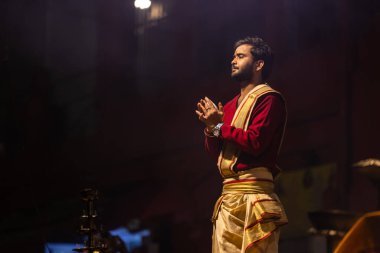Varanasi, Uttar Pradesh, Hindistan - 20 Ocak 2024: Ganga aarti, Dashashwamedh ghat geleneksel elbise ve Hindu ayinleri ile kutsal nehir keneviri akşam ayini yapan genç bir rahibin portresi.