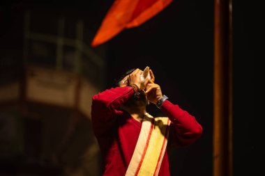 Varanasi, Uttar Pradesh, Hindistan - 20 Ocak 2024: Ganga aarti, Dashashwamedh ghat geleneksel elbise ve Hindu ayinleri ile kutsal nehir keneviri akşam ayini yapan genç bir rahibin portresi.