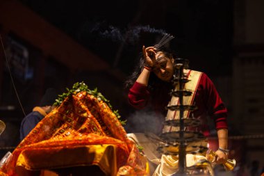 Varanasi, Uttar Pradesh, Hindistan - 20 Ocak 2024: Ganga aarti, Dashashwamedh ghat geleneksel elbise ve Hindu ayinleri ile kutsal nehir keneviri akşam ayini yapan genç bir rahibin portresi.