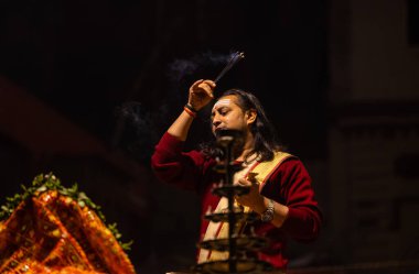 Varanasi, Uttar Pradesh, Hindistan - 20 Ocak 2024: Ganga aarti, Dashashwamedh ghat geleneksel elbise ve Hindu ayinleri ile kutsal nehir keneviri akşam ayini yapan genç bir rahibin portresi.