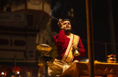 Varanasi, Uttar Pradesh, Hindistan - 20 Ocak 2024: Ganga aarti, Dashashwamedh ghat geleneksel elbise ve Hindu ayinleri ile kutsal nehir keneviri akşam ayini yapan genç bir rahibin portresi.