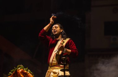 Varanasi, Uttar Pradesh, Hindistan - 20 Ocak 2024: Ganga aarti, Dashashwamedh ghat geleneksel elbise ve Hindu ayinleri ile kutsal nehir keneviri akşam ayini yapan genç bir rahibin portresi.