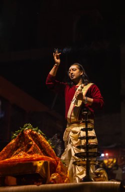 Varanasi, Uttar Pradesh, Hindistan - 20 Ocak 2024: Ganga aarti, Dashashwamedh ghat geleneksel elbise ve Hindu ayinleri ile kutsal nehir keneviri akşam ayini yapan genç bir rahibin portresi.