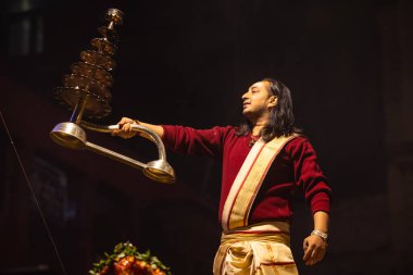 Varanasi, Uttar Pradesh, Hindistan - 20 Ocak 2024: Ganga aarti, Dashashwamedh ghat geleneksel elbise ve Hindu ayinleri ile kutsal nehir keneviri akşam ayini yapan genç bir rahibin portresi.