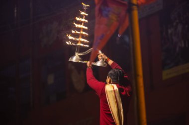Varanasi, Uttar Pradesh, Hindistan - 20 Ocak 2024: Ganga aarti, Dashashwamedh ghat geleneksel elbise ve Hindu ayinleri ile kutsal nehir keneviri akşam ayini yapan genç bir rahibin portresi.