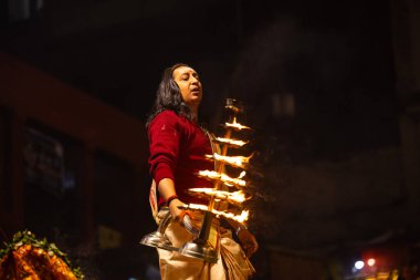 Varanasi, Uttar Pradesh, Hindistan - 20 Ocak 2024: Ganga aarti, Dashashwamedh ghat geleneksel elbise ve Hindu ayinleri ile kutsal nehir keneviri akşam ayini yapan genç bir rahibin portresi.