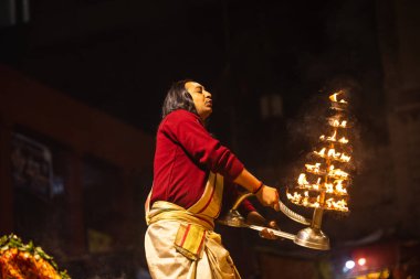 Varanasi, Uttar Pradesh, Hindistan - 20 Ocak 2024: Ganga aarti, Dashashwamedh ghat geleneksel elbise ve Hindu ayinleri ile kutsal nehir keneviri akşam ayini yapan genç bir rahibin portresi.