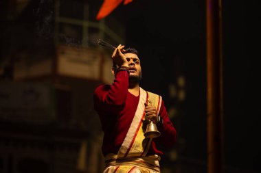 Varanasi, Uttar Pradesh, Hindistan - 20 Ocak 2024: Ganga aarti, Dashashwamedh ghat geleneksel elbise ve Hindu ayinleri ile kutsal nehir keneviri akşam ayini yapan genç bir rahibin portresi.