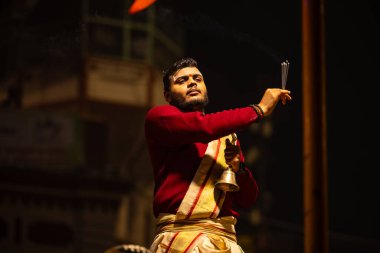 Varanasi, Uttar Pradesh, Hindistan - 20 Ocak 2024: Ganga aarti, Dashashwamedh ghat geleneksel elbise ve Hindu ayinleri ile kutsal nehir keneviri akşam ayini yapan genç bir rahibin portresi.