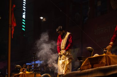 Varanasi, Uttar Pradesh, Hindistan - 20 Ocak 2024: Ganga aarti, Dashashwamedh ghat geleneksel elbise ve Hindu ayinleri ile kutsal nehir keneviri akşam ayini yapan genç bir rahibin portresi.