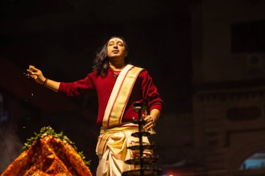 Varanasi, Uttar Pradesh, Hindistan - 20 Ocak 2024: Ganga aarti, Dashashwamedh ghat geleneksel elbise ve Hindu ayinleri ile kutsal nehir keneviri akşam ayini yapan genç bir rahibin portresi.