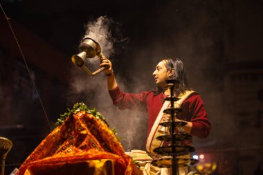 Varanasi, Uttar Pradesh, Hindistan - 20 Ocak 2024: Ganga aarti, Dashashwamedh ghat geleneksel elbise ve Hindu ayinleri ile kutsal nehir keneviri akşam ayini yapan genç bir rahibin portresi.