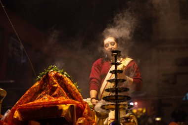 Varanasi, Uttar Pradesh, Hindistan - 20 Ocak 2024: Ganga aarti, Dashashwamedh ghat geleneksel elbise ve Hindu ayinleri ile kutsal nehir keneviri akşam ayini yapan genç bir rahibin portresi.
