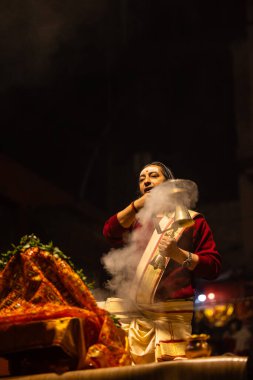 Varanasi, Uttar Pradesh, Hindistan - 20 Ocak 2024: Ganga aarti, Dashashwamedh ghat geleneksel elbise ve Hindu ayinleri ile kutsal nehir keneviri akşam ayini yapan genç bir rahibin portresi.