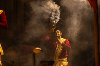 Varanasi, Uttar Pradesh, Hindistan - 20 Ocak 2024: Ganga aarti, Dashashwamedh ghat geleneksel elbise ve Hindu ayinleri ile kutsal nehir keneviri akşam ayini yapan genç bir rahibin portresi.