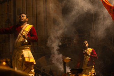 Varanasi, Uttar Pradesh, Hindistan - 20 Ocak 2024: Ganga aarti, Dashashwamedh ghat geleneksel elbise ve Hindu ayinleri ile kutsal nehir keneviri akşam ayini yapan genç bir rahibin portresi.