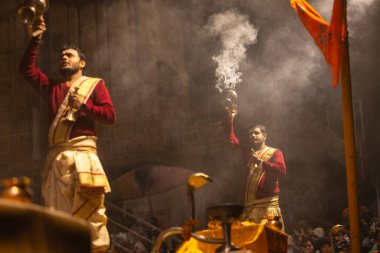 Varanasi, Uttar Pradesh, Hindistan - 20 Ocak 2024: Ganga aarti, Dashashwamedh ghat geleneksel elbise ve Hindu ayinleri ile kutsal nehir keneviri akşam ayini yapan genç bir rahibin portresi.