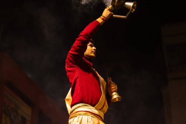 Varanasi, Uttar Pradesh, Hindistan - 20 Ocak 2024: Ganga aarti, Dashashwamedh ghat geleneksel elbise ve Hindu ayinleri ile kutsal nehir keneviri akşam ayini yapan genç bir rahibin portresi.