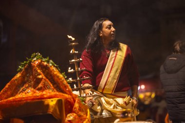 Varanasi, Uttar Pradesh, Hindistan - 20 Ocak 2024: Ganga aarti, Dashashwamedh ghat geleneksel elbise ve Hindu ayinleri ile kutsal nehir keneviri akşam ayini yapan genç bir rahibin portresi.