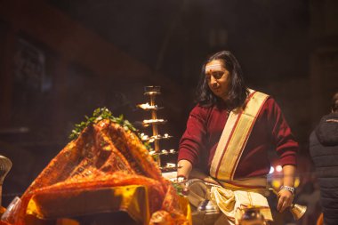 Varanasi, Uttar Pradesh, Hindistan - 20 Ocak 2024: Ganga aarti, Dashashwamedh ghat geleneksel elbise ve Hindu ayinleri ile kutsal nehir keneviri akşam ayini yapan genç bir rahibin portresi.