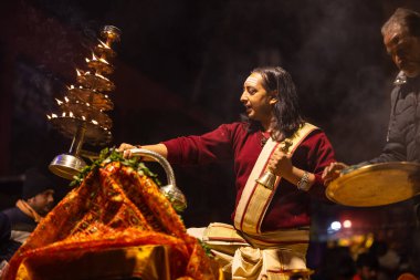 Varanasi, Uttar Pradesh, Hindistan - 20 Ocak 2024: Ganga aarti, Dashashwamedh ghat geleneksel elbise ve Hindu ayinleri ile kutsal nehir keneviri akşam ayini yapan genç bir rahibin portresi.