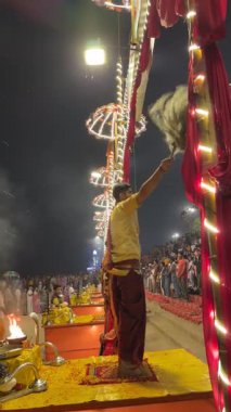 Varanasi, Uttar Pradesh, Hindistan - 12 Mart 2025: Ganga aarti, genç erkek rahibin Dashashwamedh ghat 'ında akşamüstü geleneksel Hint ayinleri ile geleneksel elbise içinde kutsal nehir ganghatlarını sahnelediği video..