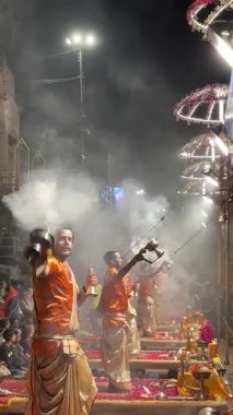 Varanasi, Uttar Pradesh, Hindistan - 12 Mart 2025: Ganga aarti, Dashashwamedh ghat 'ta akşam saatlerinde Hint ritüelleri ile geleneksel elbise içinde nehir çeteleri yakınlarındaki ışık ve dekorasyon videosu.