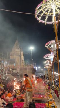 Varanasi, Uttar Pradesh, Hindistan - 12 Mart 2025: Ganga aarti, Dashashwamedh ghat 'ta akşam saatlerinde Hint ritüelleri ile geleneksel elbise içinde nehir çeteleri yakınlarındaki ışık ve dekorasyon videosu.