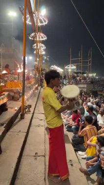 Varanasi, Uttar Pradesh, Hindistan - 12 Mart 2025: Ganga aarti, Dashashwamedh ghat 'ta akşam saatlerinde Hint ritüelleri ile geleneksel elbise içinde nehir çeteleri yakınlarındaki ışık ve dekorasyon videosu.