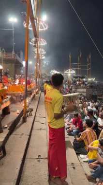 Varanasi, Uttar Pradesh, Hindistan - 12 Mart 2025: Ganga aarti, Dashashwamedh ghat 'ta akşam saatlerinde Hint ritüelleri ile geleneksel elbise içinde nehir çeteleri yakınlarındaki ışık ve dekorasyon videosu.