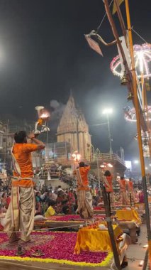 Varanasi, Uttar Pradesh, Hindistan - 12 Mart 2025: Ganga aarti, Dashashwamedh ghat 'ta akşam saatlerinde Hint ritüelleri ile geleneksel elbise içinde nehir çeteleri yakınlarındaki ışık ve dekorasyon videosu.