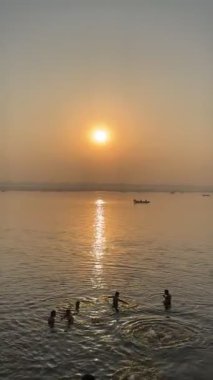 Varanasi, Uttar Pradesh, Hindistan - 12 Mart 2025: Varanasi 'de kış sabahı gündoğumunda nehir keneviri kıyısında yüzen veya parkedilmiş tahta botların sinematografik görüntüsü.