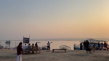 Varanasi, Uttar Pradesh, Hindistan - 12 Mart 2025: Varanasi 'de kış sabahı gündoğumunda nehir keneviri kıyısında yüzen veya parkedilmiş tahta botların sinematografik görüntüsü.