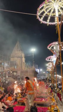 Varanasi, Uttar Pradesh, Hindistan - 12 Mart 2025: Ganga aarti, Dashashwamedh ghat 'ta akşam saatlerinde Hint ritüelleri ile geleneksel elbise içinde nehir çeteleri yakınlarındaki ışık ve dekorasyon videosu.