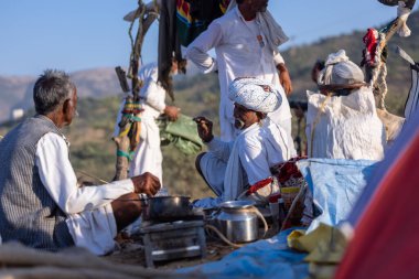 Puşkar, Rajasthan, Hindistan - 09 Kasım 2024: Çöldeki fuar alanında develerin ticareti sırasında geleneksel giysili bir Rajasthani halkının portresi.