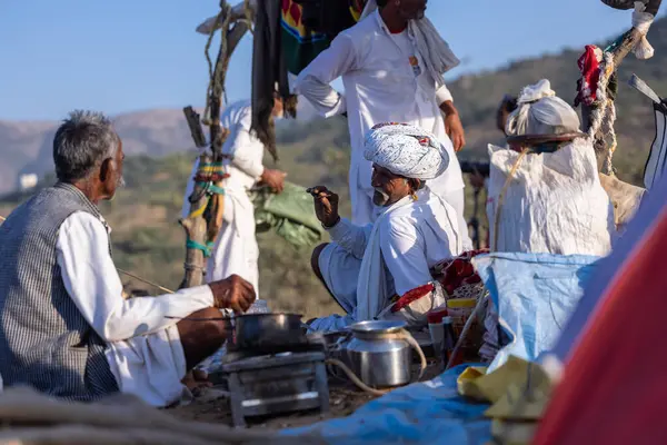 Puşkar, Rajasthan, Hindistan - 09 Kasım 2024: Çöldeki fuar alanında develerin ticareti sırasında geleneksel giysili bir Rajasthani halkının portresi.
