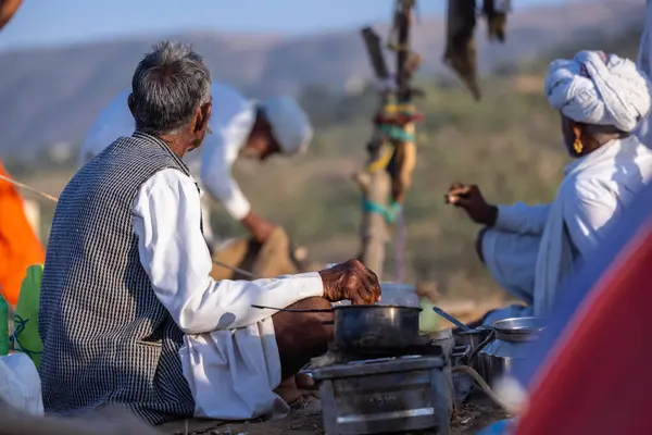 Puşkar, Rajasthan, Hindistan - 09 Kasım 2024: Çöldeki fuar alanında develerin ticareti sırasında geleneksel giysili bir Rajasthani halkının portresi.