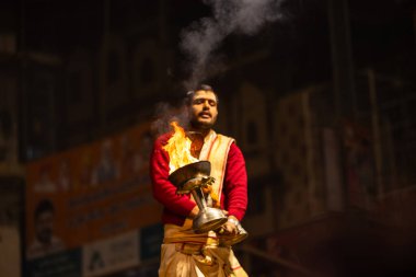 Varanasi, Uttar Pradesh, Hindistan - 20 Ocak 2024: Ganga aarti, Geleneksel elbise içinde Dashashwamedh ghat kutsal nehir keneviri akşam ayini yapan kimliği belirsiz genç bir erkek rahibin portresi.