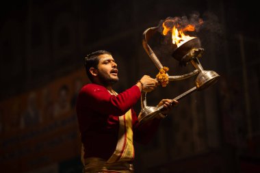 Varanasi, Uttar Pradesh, Hindistan - 20 Ocak 2024: Ganga aarti, Geleneksel elbise içinde Dashashwamedh ghat kutsal nehir keneviri akşam ayini yapan kimliği belirsiz genç bir erkek rahibin portresi.
