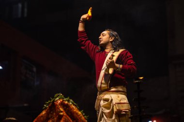 Varanasi, Uttar Pradesh, Hindistan - 20 Ocak 2024: Ganga aarti, Geleneksel elbise içinde Dashashwamedh ghat kutsal nehir keneviri akşam ayini yapan kimliği belirsiz genç bir erkek rahibin portresi.