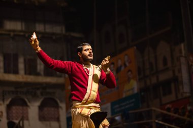 Varanasi, Uttar Pradesh, Hindistan - 20 Ocak 2024: Ganga aarti, Geleneksel elbise içinde Dashashwamedh ghat kutsal nehir keneviri akşam ayini yapan kimliği belirsiz genç bir erkek rahibin portresi.