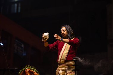 Varanasi, Uttar Pradesh, Hindistan - 20 Ocak 2024: Ganga aarti, Geleneksel elbise içinde Dashashwamedh ghat kutsal nehir keneviri akşam ayini yapan kimliği belirsiz genç bir erkek rahibin portresi.