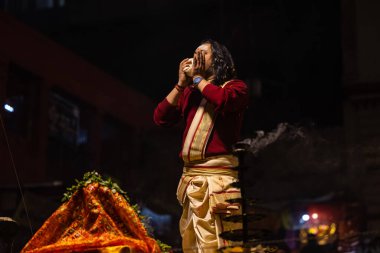 Varanasi, Uttar Pradesh, Hindistan - 20 Ocak 2024: Ganga aarti, Geleneksel elbise içinde Dashashwamedh ghat kutsal nehir keneviri akşam ayini yapan kimliği belirsiz genç bir erkek rahibin portresi.