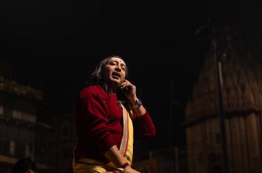 Varanasi, Uttar Pradesh, Hindistan - 20 Ocak 2024: Ganga aarti, Geleneksel elbise içinde Dashashwamedh ghat kutsal nehir keneviri akşam ayini yapan kimliği belirsiz genç bir erkek rahibin portresi.