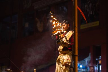 Varanasi, Uttar Pradesh, Hindistan - 20 Ocak 2024: Ganga aarti, Geleneksel elbise içinde Dashashwamedh ghat kutsal nehir keneviri akşam ayini yapan kimliği belirsiz genç bir erkek rahibin portresi.