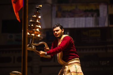 Varanasi, Uttar Pradesh, Hindistan - 20 Ocak 2024: Ganga aarti, Geleneksel elbise içinde Dashashwamedh ghat kutsal nehir keneviri akşam ayini yapan kimliği belirsiz genç bir erkek rahibin portresi.