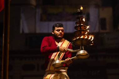Varanasi, Uttar Pradesh, Hindistan - 20 Ocak 2024: Ganga aarti, Geleneksel elbise içinde Dashashwamedh ghat kutsal nehir keneviri akşam ayini yapan kimliği belirsiz genç bir erkek rahibin portresi.